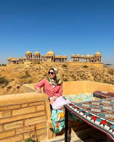 a woman sitting on a bed in front of a building at Hotel Royal Heritage in Jaisalmer