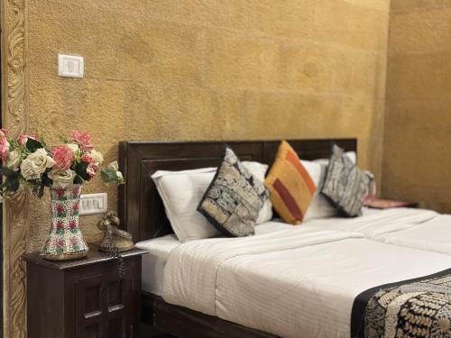 a bedroom with a bed and a vase of flowers on a table at Hotel Royal Heritage in Jaisalmer