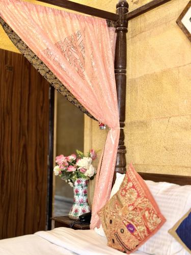 a bed with a vase of flowers and a curtain at Hotel Royal Heritage in Jaisalmer
