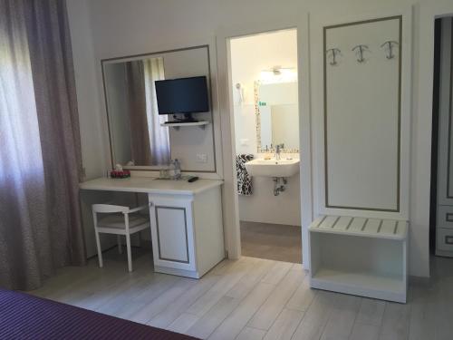 baño con lavabo y escritorio con TV en Albergo Ester, en Piandimeleto