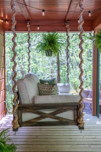 a porch swing with a white couch on a porch at Fall25 Offhottubviewsfirepitwcu3minfamilies in Sylva