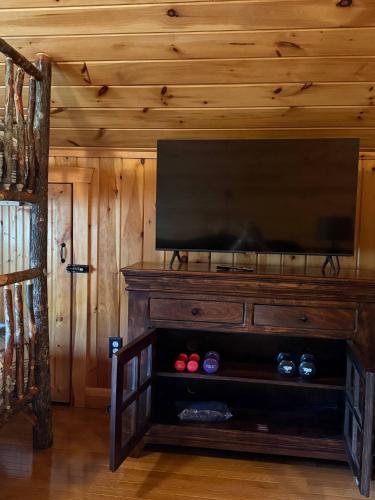 a flat screen tv on top of a wooden entertainment center at Fall25 Offhottubviewsfirepitwcu3minfamilies in Sylva