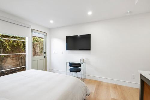 a bedroom with a bed and a tv on the wall at Casa Jardin - Boutique Suites in Downtown Santa Barbara in Santa Barbara