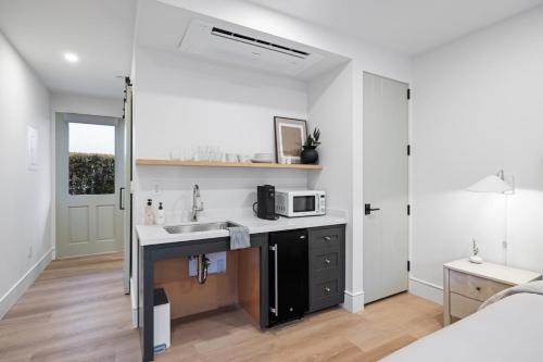 a small kitchen with a sink and a microwave at Casa Jardin - Boutique Suites in Downtown Santa Barbara in Santa Barbara