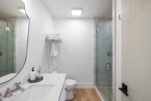 a bathroom with a toilet and a glass shower at Casa Jardin - Boutique Suites in Downtown Santa Barbara in Santa Barbara