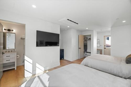 a white bedroom with two beds and a mirror at Casa Jardin - Boutique Suites in Downtown Santa Barbara in Santa Barbara