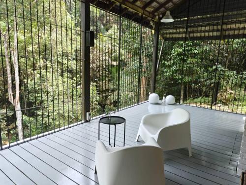 a screened porch with white chairs and a table at LilyJoe Treehouse Serendah in Serendah