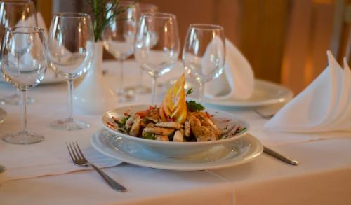 a plate of food on a table with wine glasses at Hotel - Restaurant Gonduzo in Odorheiu Secuiesc
