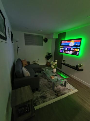 a living room with a couch and a tv with green lights at ArbyManie's Place Newly Built Apartment in London