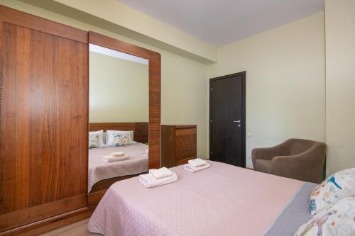 1 dormitorio con cama y espejo con toallas en Cozy stay rentals - cozy & bright apartment with 1BR in Tbilisi, en Tiflis