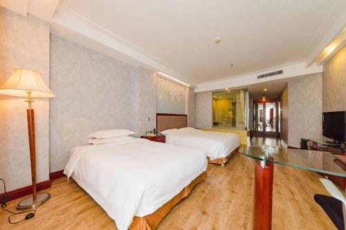 a hotel room with two beds and a television at Junyu Grand Hotel Qinhuangdao in Qinhuangdao