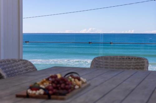 a plate of fruit on a table with a view of the ocean at Seabreeze on the Beach in Barrack Point