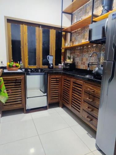 a kitchen with wooden cabinets and a refrigerator at Flat de Irinha Moreré in Cayru