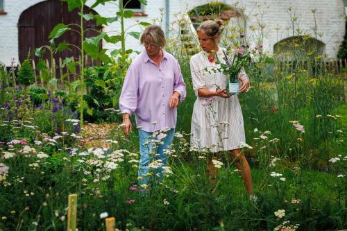 two women walking through a garden with flowers at Zee-van-Tijd in Oudenburg