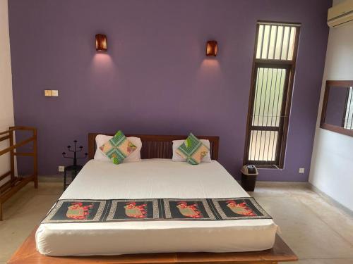 a bedroom with a large bed with purple walls at Vanaro Resort in Yala