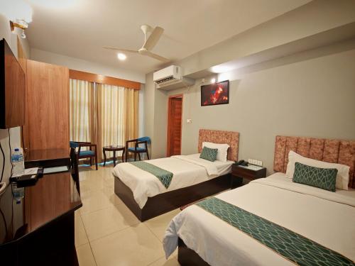 a hotel room with two beds and a television at Sylhet Paradise Inn in Sylhet