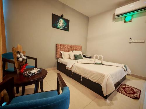 a bedroom with two beds and a table and a chair at Sylhet Paradise Inn in Sylhet