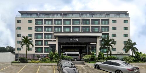 Un gran edificio blanco con coches aparcados en un estacionamiento. en Dancenter Luxury Retreat Angeles City Pampanga Formerly Hevea Resort, en Ángeles