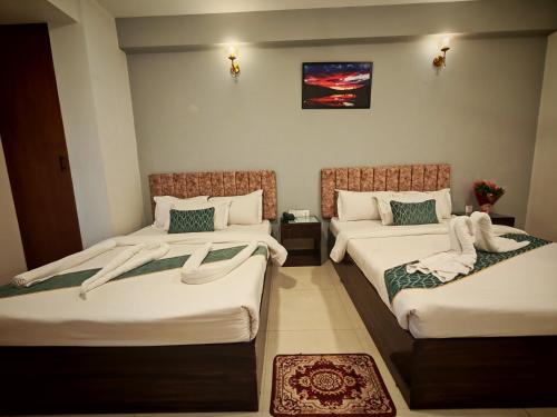 a hotel room with two beds with white sheets at Sylhet Paradise Inn in Sylhet