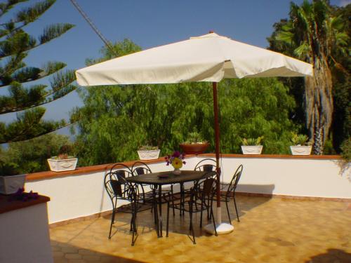 einen Tisch und Stühle unter einem Sonnenschirm auf einer Terrasse in der Unterkunft Villa Isabella in Zambrone