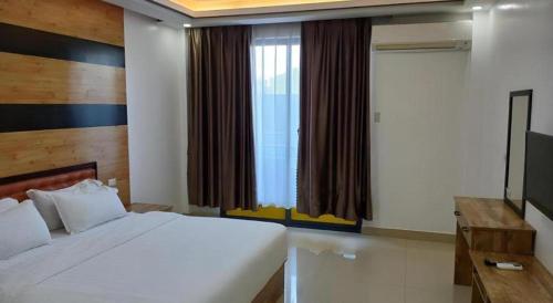 a bedroom with a bed and a large window at Hotel Primera in Zamboanga