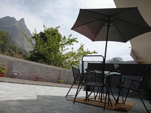 a table and chairs with an umbrella on a patio at Danny's Rural Suite T2 in Curral das Freiras