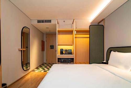 a small bedroom with a bed and a mirror at ARTOTEL Living World Kota Wisata 