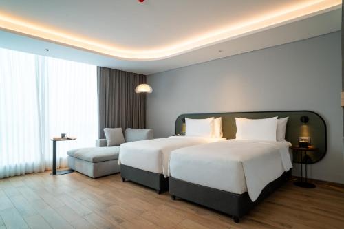 a hotel room with two beds and a couch at ARTOTEL Living World Kota Wisata 