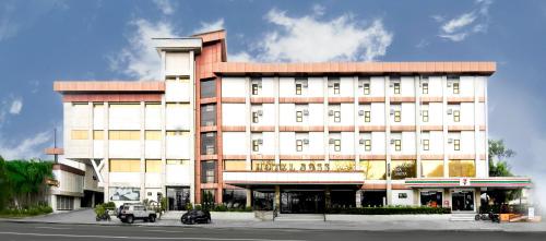 a large white building with a red roof at Dancenter Boss Hotel Near Clark International Airport in Angeles