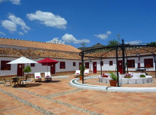 a courtyard with tables and umbrellas in a building at Hotel Cortijo del Arte - Caminito del Rey in Pizarra