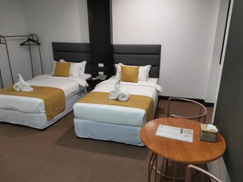 a hotel room with two beds and a table at Dancenter Boss Hotel Near Clark International Airport in Angeles
