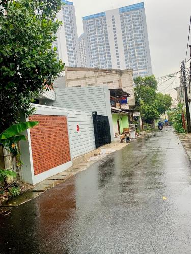 una strada bagnata con un edificio e palazzi alti di Thiago living Syariah a Giacarta