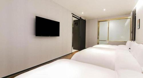 a bedroom with two beds and a tv on the wall at Gimhae Perfect Hotel in Gimhae