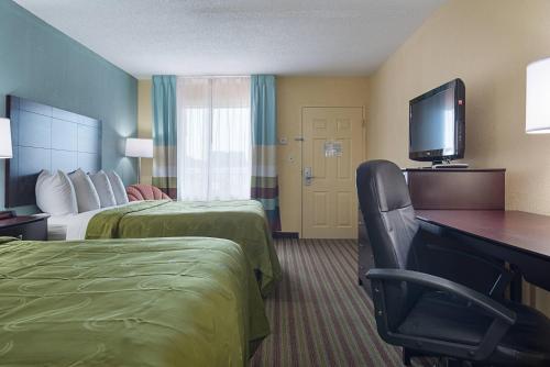 a hotel room with two beds and a desk and a television at Quality Inn Calhoun North I-75 in Calhoun