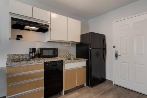 a kitchen with a black refrigerator and a sink at MainStay Suites Denver Tech Center in Centennial