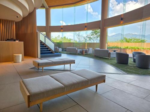 a lobby with a couch and chairs and windows at Hotel Yumeshizuku in Minami Aso