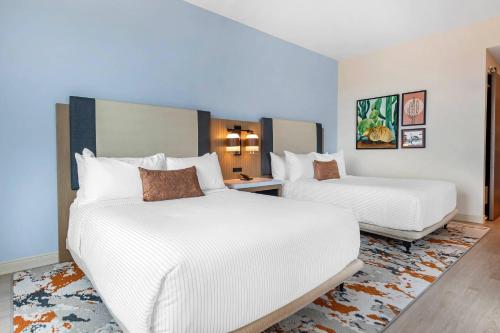 two beds in a hotel room with white sheets at Cambria Hotel Austin Downtown in Austin