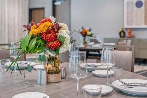 a vase of flowers on a table with plates and glasses at Cambria Hotel Austin Downtown in Austin