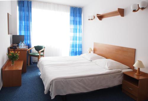 a bedroom with a large white bed and a desk at ELPAK Świnoujście in Świnoujście
