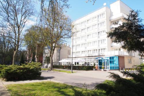 a white building with a blue door in a park at ELPAK Świnoujście in Świnoujście