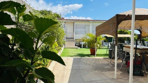 a patio with a table and chairs and an umbrella at Finca Maradentro - private pool and jacuzzi with ocean view in Arafo