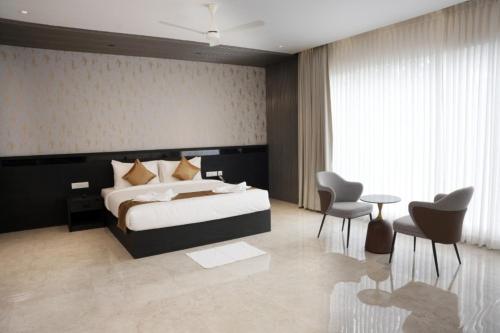 a bedroom with a bed and a table and chairs at Alba Regency in Guruvāyūr