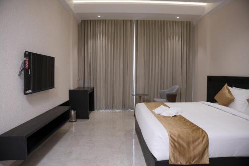 a hotel room with a bed and a television at Alba Regency in Guruvāyūr