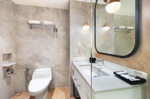 a bathroom with a toilet and a sink and a mirror at Luwansa Hotel and Convention Center Manado in Manado
