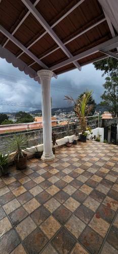 an outdoor patio with a pillar and plants on a roof at Elevate Ooty in Ooty