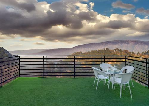 a table and chairs on a balcony with a view at ExoticStays l Empire Kasauli in Kasauli