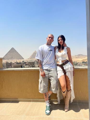 a man and a woman standing in front of the pyramids at Tiye Pyramids Hotel in Cairo