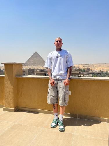 a man standing on a ledge with a view of the pyramids at Tiye Pyramids Hotel in Cairo