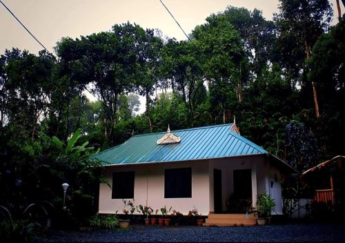 a small white house with a green roof at Mist Nest Munnar in Munnar