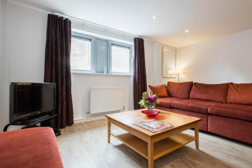 a living room with a red couch and a table at PREMIER SUITES Newcastle in Newcastle upon Tyne